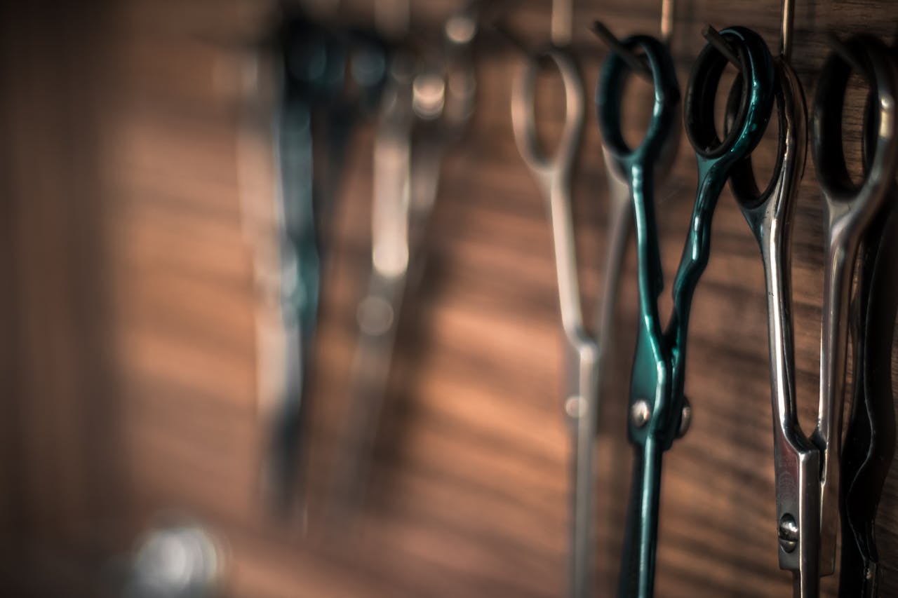 services-bg A detailed view of professional haircutting scissors hanging on a wooden wall in a barbershop.