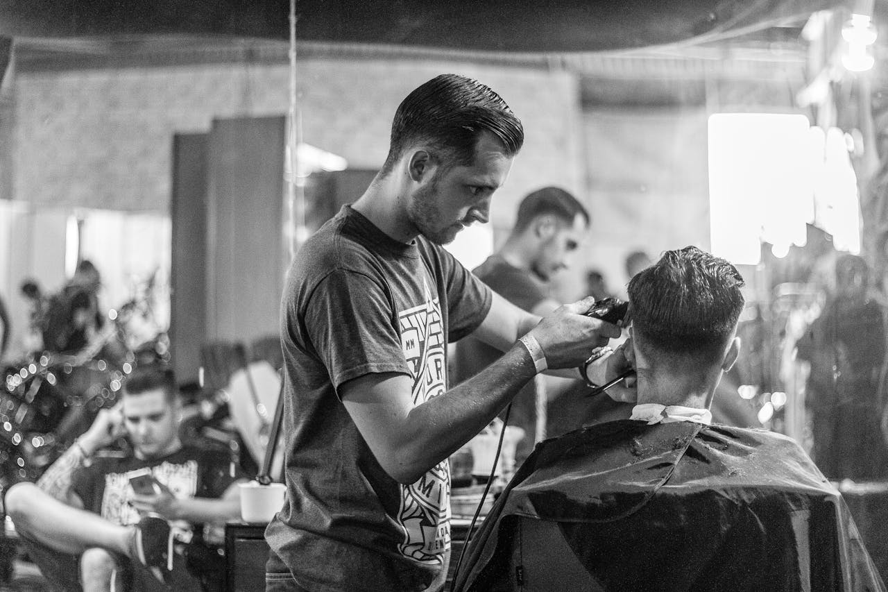 A barber skillfully gives a haircut in a stylish Wrocław barbershop, captured in moody monochrome.